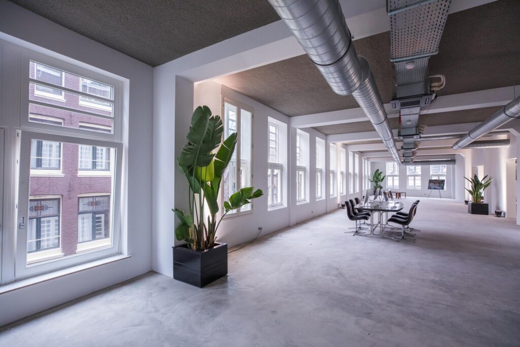 Licht en modern kantoorinterieur aan de Prins Hendrikkade met grote ramen, industriële details en tropische planten.